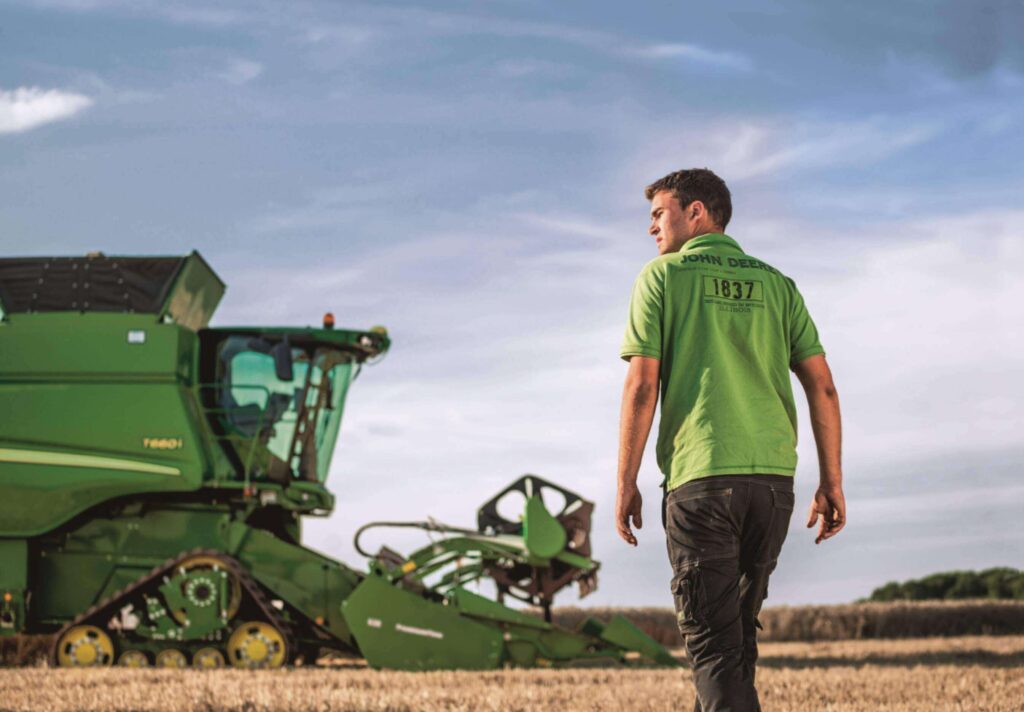 John Deere T-Serie mit Mitarbeiter der auf den Mähdrescher zu läuft