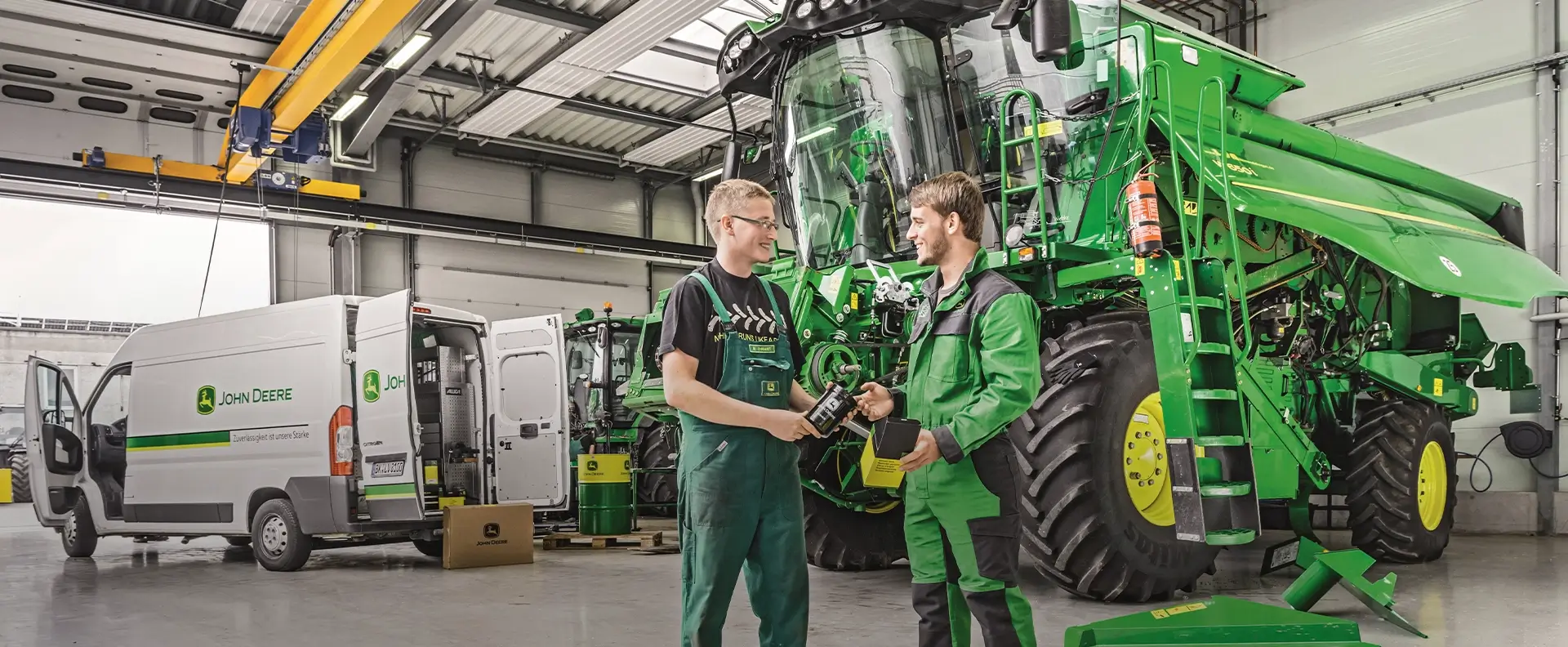 2 junge Männer in Arbeitskleidung im Maschinenhalle von John Deere