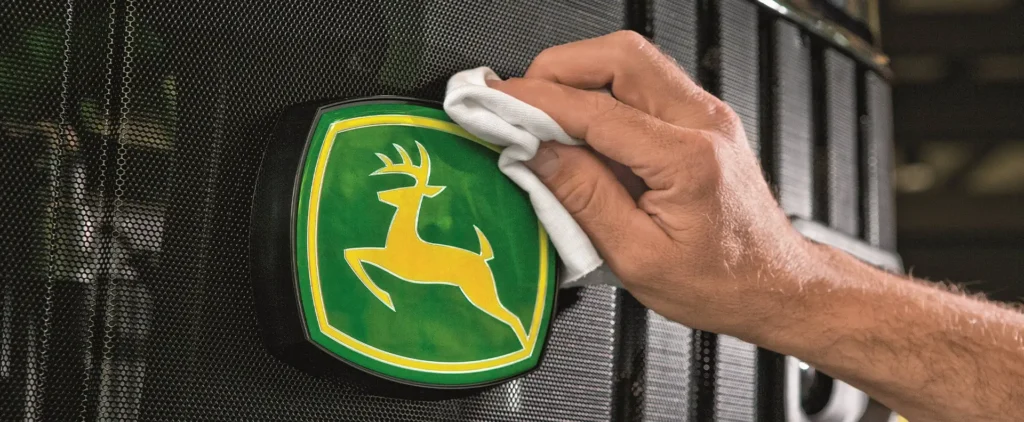 Mann putzt John Deere Logo