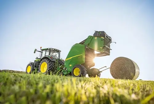 John Deere Ballenpresse mit fertigem Ballen auf dem Feld