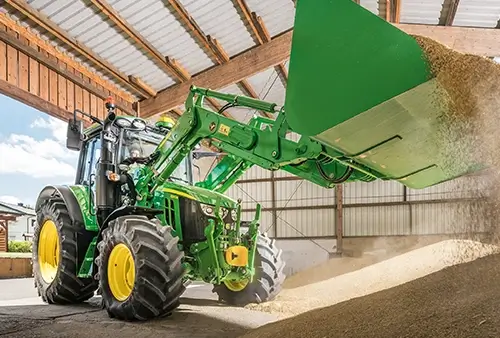 John Deere Frontlader kippt Späne in Scheune