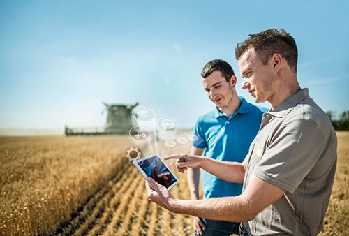 2 Männer schauen auf ein Tablet, auf dem Feld